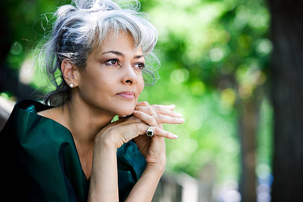 Elegant lady with grey hair and blue eyes modeling a rich emerald green ensemble